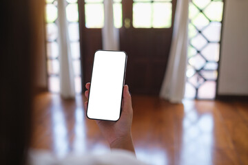 Wall Mural - mockup image of a woman holding mobile phone with blank desktop screen at home