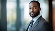 © Jolin - Confident African American businessman in suit, soft light, blurred office background, exuding professionalism and determination.