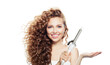 © artmim - Isolated woman with healthy long wavy hair  holding empty palm hand and using curlyng iron, fashion beauty portrait