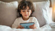 © Quang - Child engaged with smartphone while sitting comfortably in bed