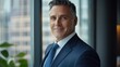© Yevhen - Confident Middle-Aged Business Executive Smiling at Office Window - Portrait of a Mature Male Leader