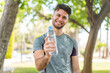 © luismolinero - Young handsome sport man with a bottle of water at outdoors with happy expression