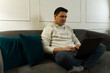 © AntonioDiaz - Remote freelancer concentrating on laptop, working comfortably from home living room workspace