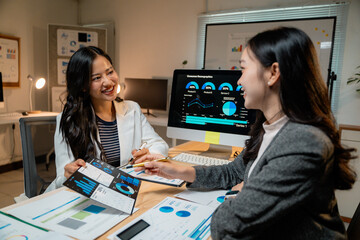 Poster - Asian businesswomen discussing marketing strategy analyzing statistical charts displayed on computer screen and printed documents