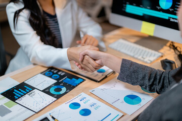 Fototapete - Businesswomen shaking hands after successful deal over financial charts
