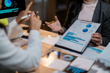 Poster - Businesswomen discussing marketing strategy showing charts and graphs on clipboard and computer screen
