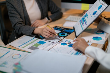 Poster - Businesswomen analyzing financial charts and graphs at office desk
