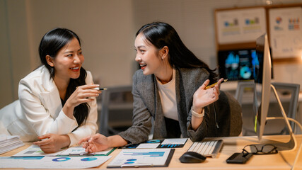 Poster - Two businesswomen discussing marketing strategy analyzing financial statistics data in office at night