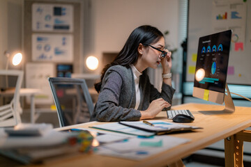 Poster - Focused businesswoman analyzing charts on computer in modern office at night