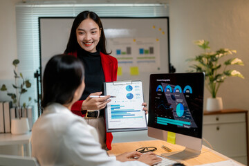 Poster - Asian businesswomen discussing and analyzing financial graphs on clipboard and computer screen