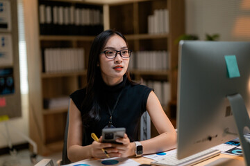Poster - Asian businesswoman working with computer and smartphone in office at night