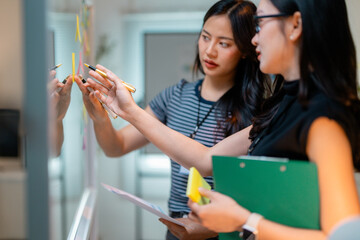 Poster - Businesswomen using sticky notes and sharing ideas on whiteboard during meeting