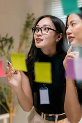 Fototapete - Businesswomen planning and brainstorming using sticky notes on glass wall in the office