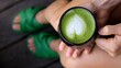 © Sia - Female relaxing on wooden porch, wearing green slippers, holding matcha latte with heart shaped foam art, enjoying peaceful moment of wellness and comfort during break