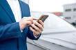 © zinkevych - Businessman in suit holding smartphone at dealership