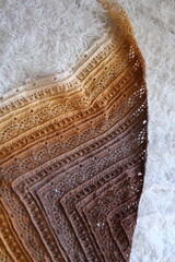Poster - A close-up shot of a warm and cozy knitted shawl lying on a pure white blanket.