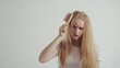 © Dao - Unhappy disappointed young woman with hair loss condition, showing hair brush, blonde caucasian girl with unhealthy hair standing on white background