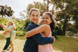 © Jacob Lund - Two friends hugging outdoors on a sunny day with laughter in the background