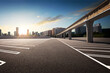 © Image Craft - Sunset scene empty parking lot under the train monorail railway with city background.