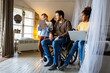 © NDABCREATIVITY - Happy father in wheelchair with interracial daughters using laptop together, education, fun concept