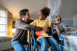 © NDABCREATIVITY - Happy multiethnic family. Smiling girl with disability in wheelchair enjoying moment with her family