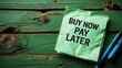 © Giovanni - blank notepad displaying the text buy now pay later on a green wooden surface