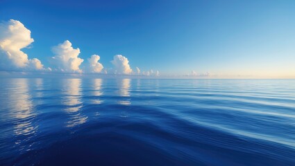 Poster - A bright blue morning sky with clear white clouds and an ocean in deep indigo during daylight. The atmosphere feels calm, cool, and relaxing. A concept for a cold background with copy space at the ...