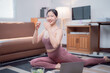© Tj - Happy asian woman practicing yoga in her living room, following an online class on her laptop and eating a healthy salad after the training