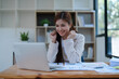© Jirapong - Confident business woman smiling Show successful gestures at her desk with market charts and documents in office