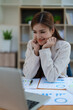 © Jirapong - Confident business woman smiling Show successful gestures at her desk with market charts and documents in office