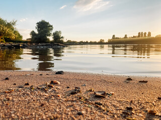 Wall Mural - beautiful lake with a sandy beach and trees in the background. the water is calm and the sky is clea
