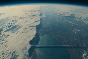 Poster - View from space capturing a vast landscape with clouds and a prominent bridge over water