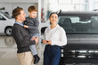© Serhii - Family in a car dealership. Happy family choosing a new car in a showroom