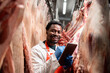 © littlewolf1989 - Food factory supervisor controlling quality and checking inventory of raw meat in slaughterhouse cold storage.