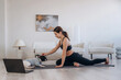 © standret - Laptop is on the floor. Woman with pug dog is doing yoga at home