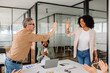 © Vadim Pastuh - A team leader and a businesswoman exchange a high-five in a collaborative office setting while teammates cheer. A representation of teamwork, celebration, and motivation in the corporate world.