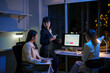 Business team working late at night, analyzing financial charts on a computer screen in an office filled with city lights and ambition