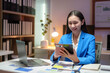 © Crystal - Young professional woman working diligently with a laptop while using a tablet in a well lit office during the evening hours