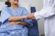 © Crystal - Doctor is holding hand of smiling patient lying in hospital bed, showing empathy and support