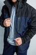 © DSMT - A man is wearing a stylish black and blue jacket that has a hood