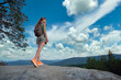 © bilanol - Healthy lifestyle concept. Hiker woman standing on mountain footpath enjoying nature during her travel on wilderness trail. Lonely female traveler traversing high hilltop route