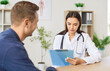 © Studio Romantic - Young man patient talking to female friendly doctor in her office in clinic during medical examination. Woman physician listening to the patient's complaints. Healthcare and medicine concept.