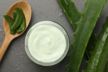 Wall Mural - moisturizing cream with extract of aloe vera in jar, cut leaves, spoon and water drops on grey backg