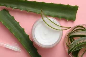 Wall Mural - moisturizing cream with extract of aloe vera in jar and cut leaves on pink background, flat lay