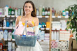 © JackF - Positive young woman with full basket choosing something in household goods shop in summer