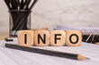 © Maks_Lab - Wooden cubes with 'INFO' text on financial documents, symbolizing business information and data.