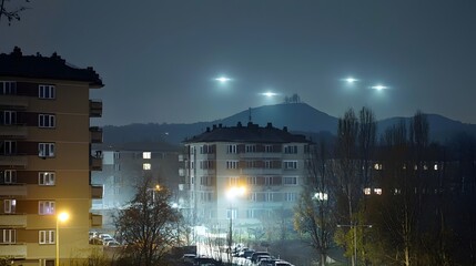 Poster - Mysterious glowing lights appear to hover in the night sky above the urban landscape defying conventional understanding of physical phenomena