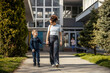 © Dusan Petkovic - Full length of a young mother holding hands with her son in front of kindergarten.