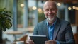 © ifoto - A man in a suit smiles while using a tablet in a cafe.