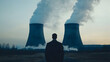 © Tursz - Contemplative figure overlooks immense nuclear power plant with smoking towers